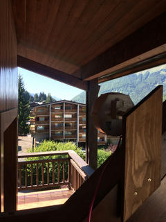 A MikroTik SXT mounted on a beam of a roof, aimed across a populated Alpine valley.